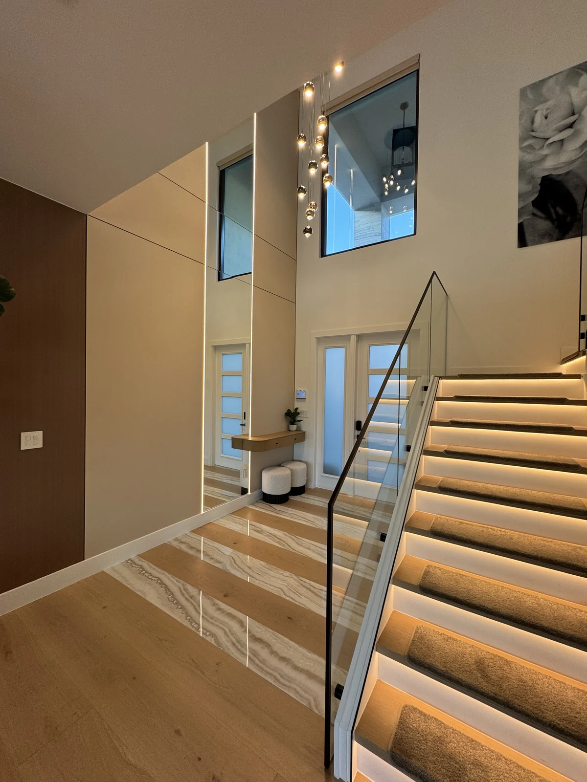 Foyer with floating staircase and backlit steps — interior design by TRE Interiors