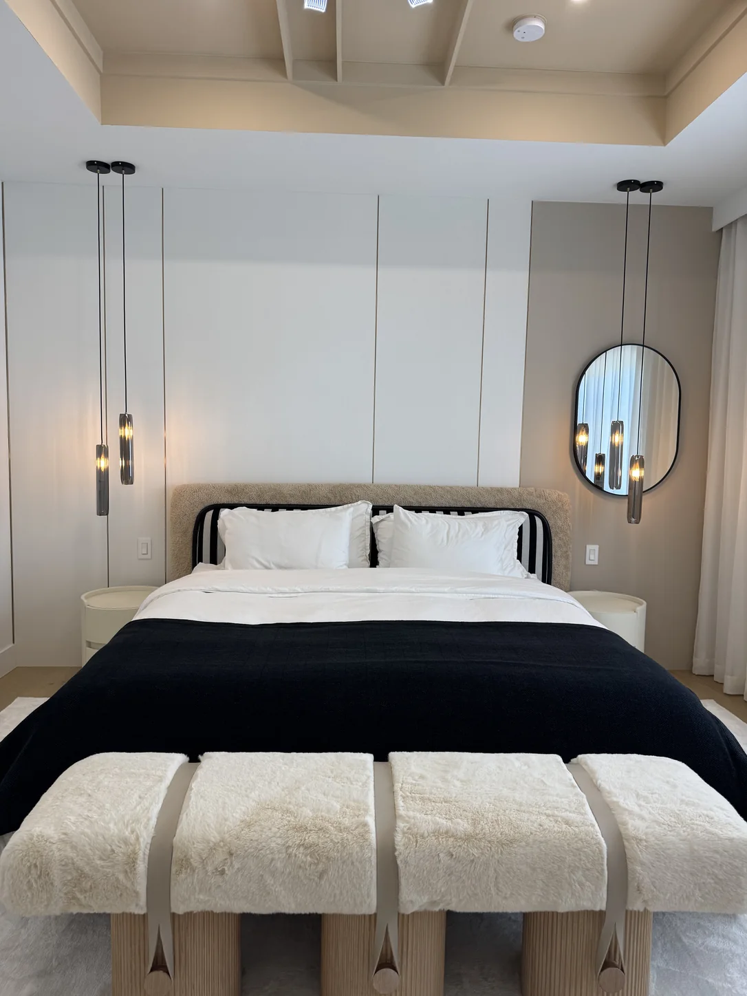 The same bedroom finished: panelled headboard wall, pendant lights, upholstered bed and bench — after
