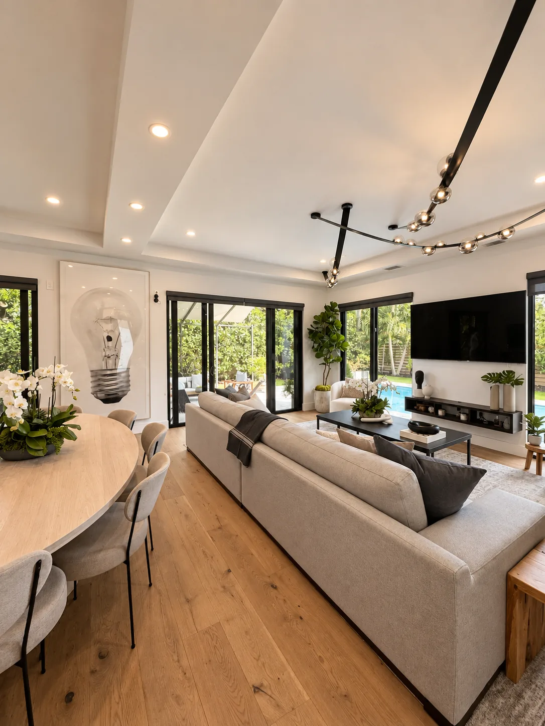 The same living room furnished: sectional sofa, oval dining table, media wall and art — after