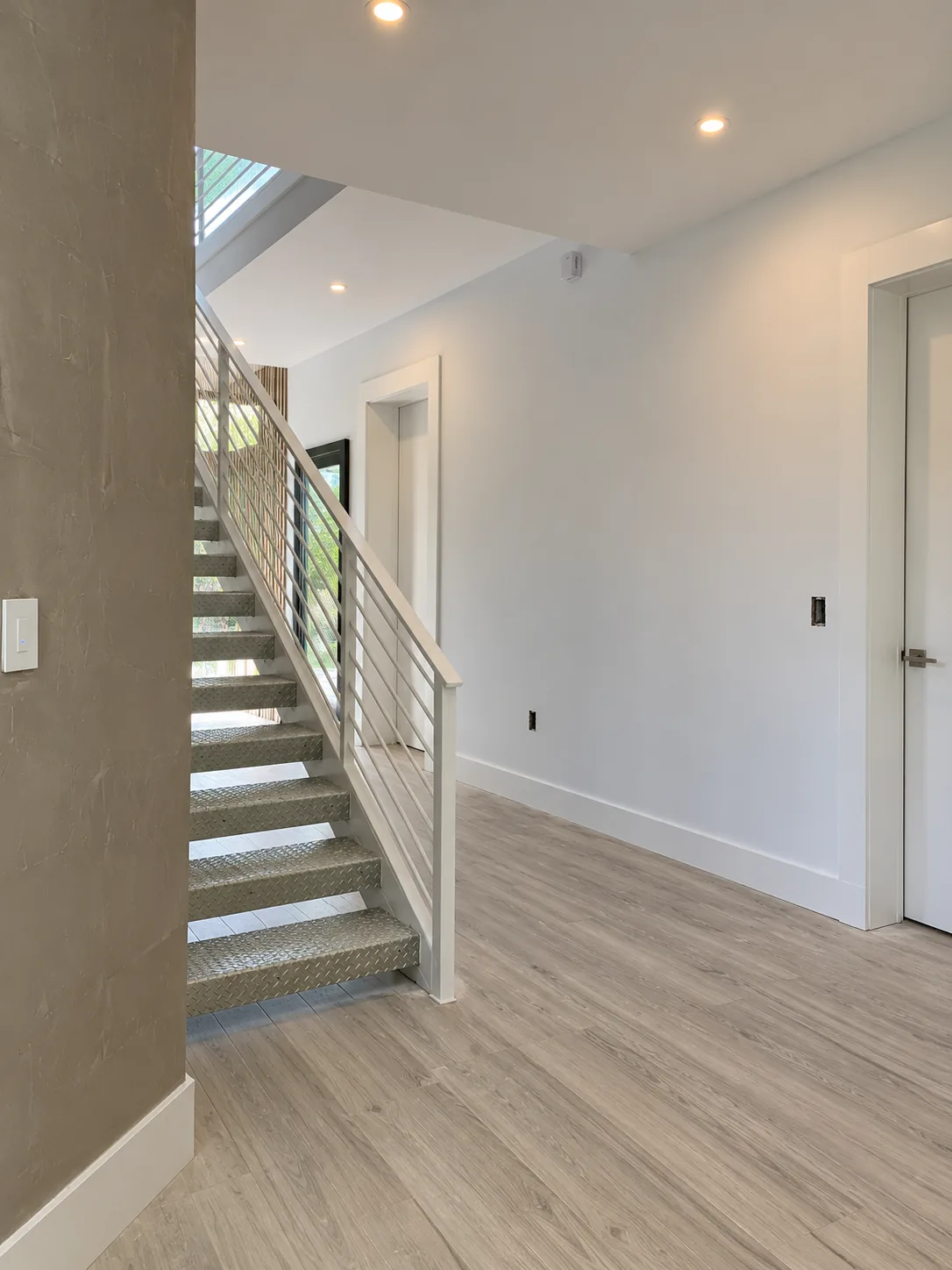 Foyer with open staircase and metal railing — before