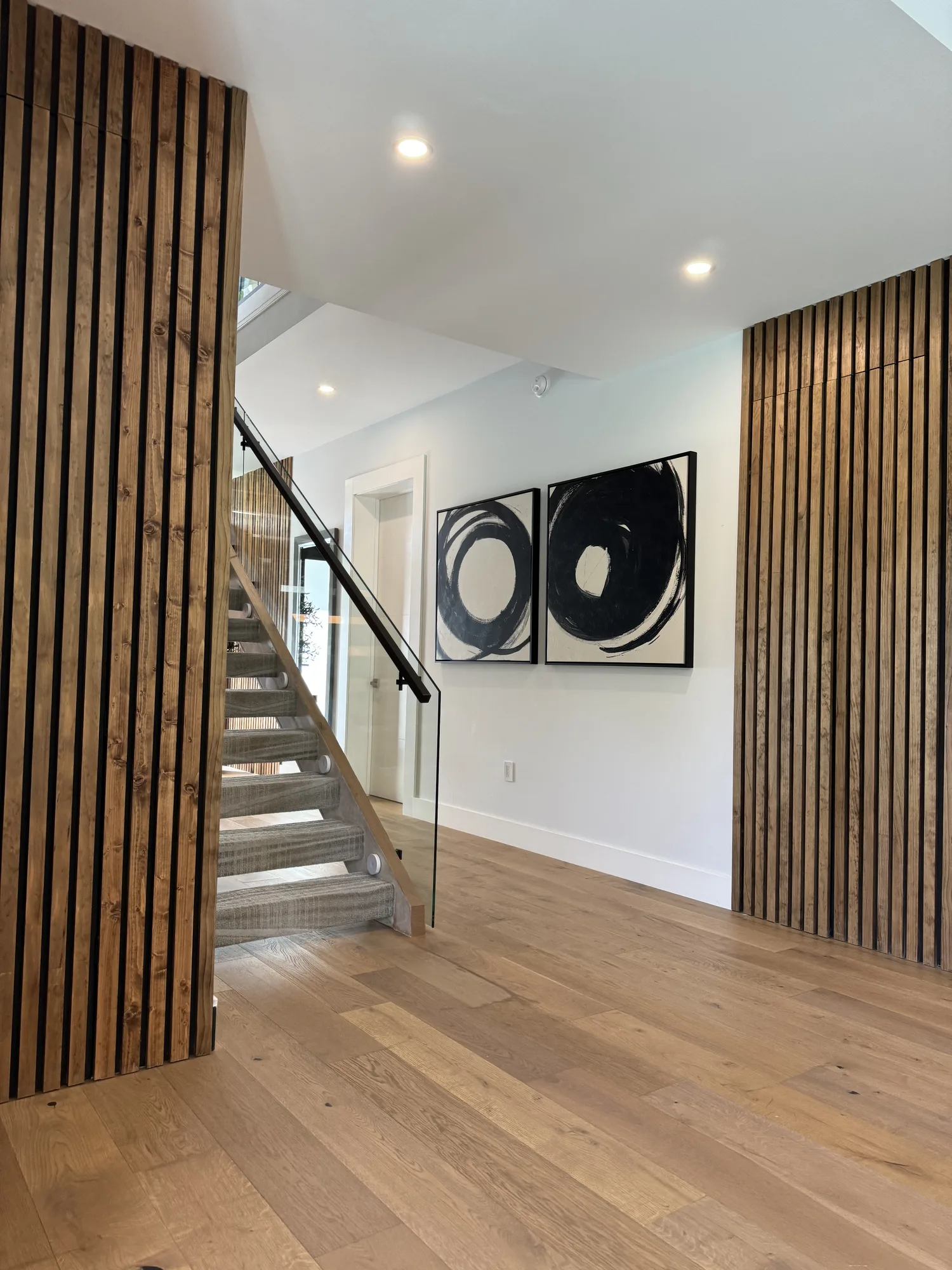Two full-height walnut slat panels framing a floating staircase