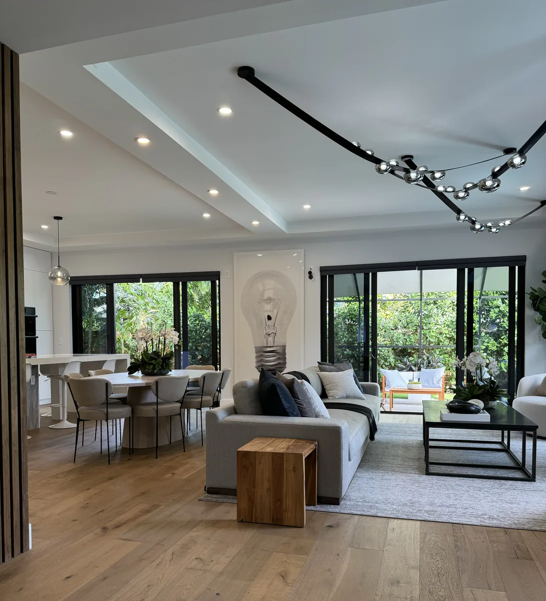 Contemporary Retreat — open-plan living room with track lighting and sliding glass doors to the pool