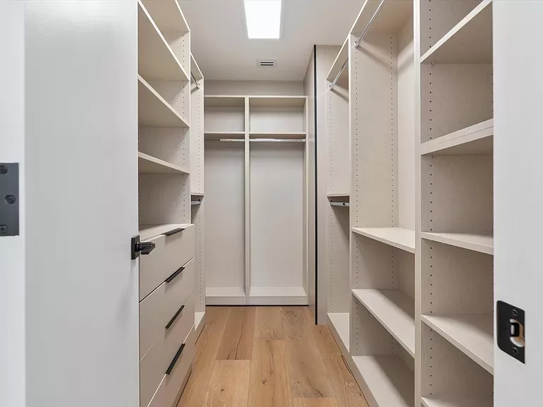 Walk-in closet with open shelving, hanging sections and a drawer tower
