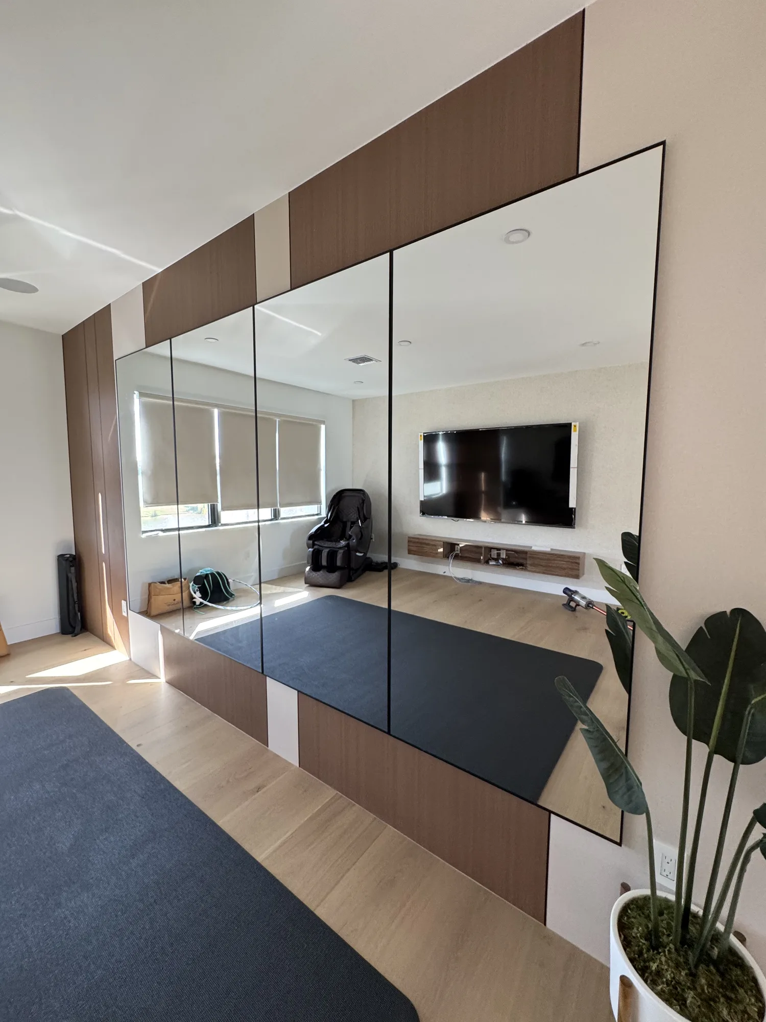 Feature wall of wood-veneer panels and full-height mirrors around a wall-mounted TV