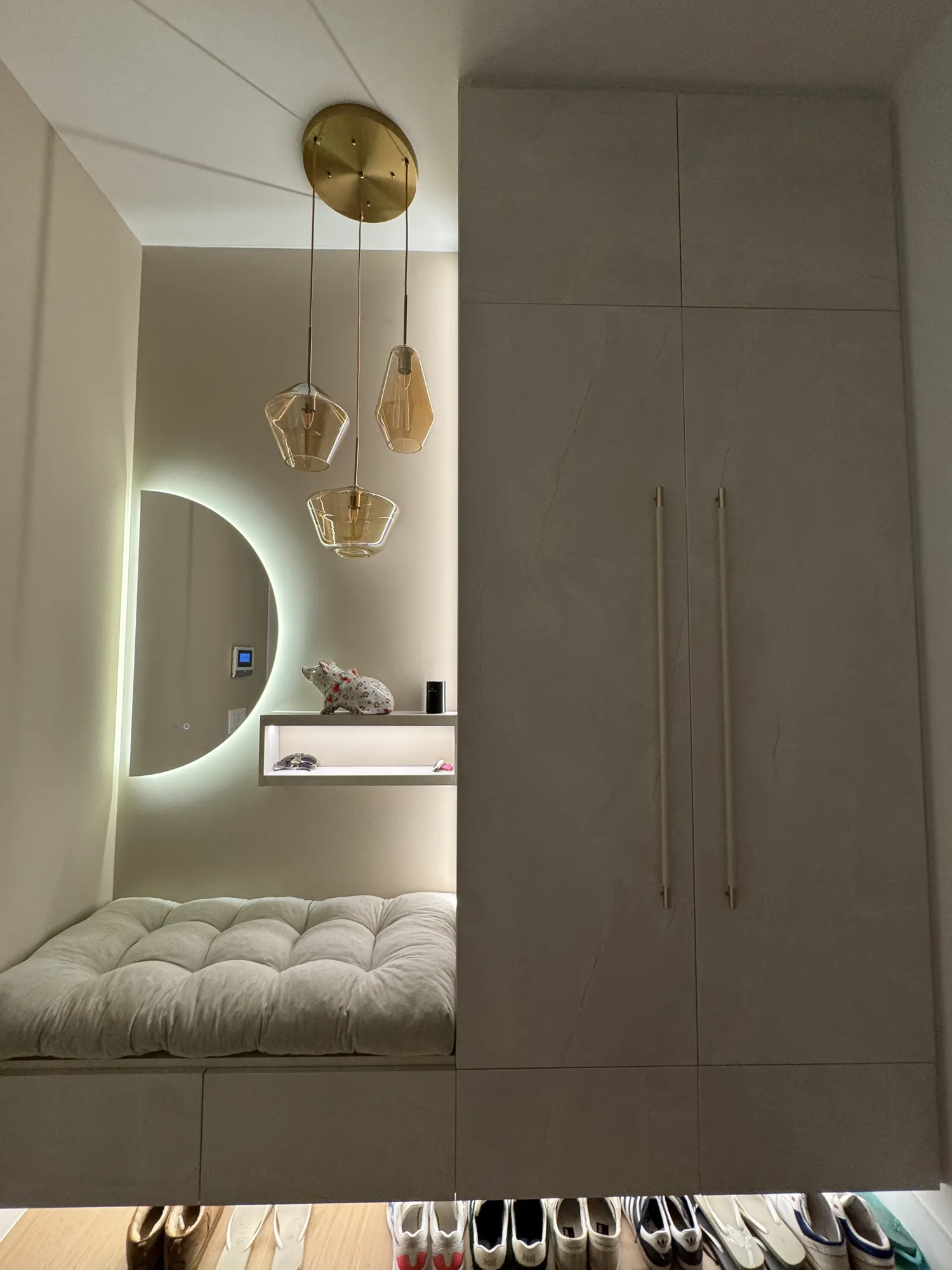 Floor-to-ceiling wardrobe with long pulls next to an upholstered bench niche and a lit shelf